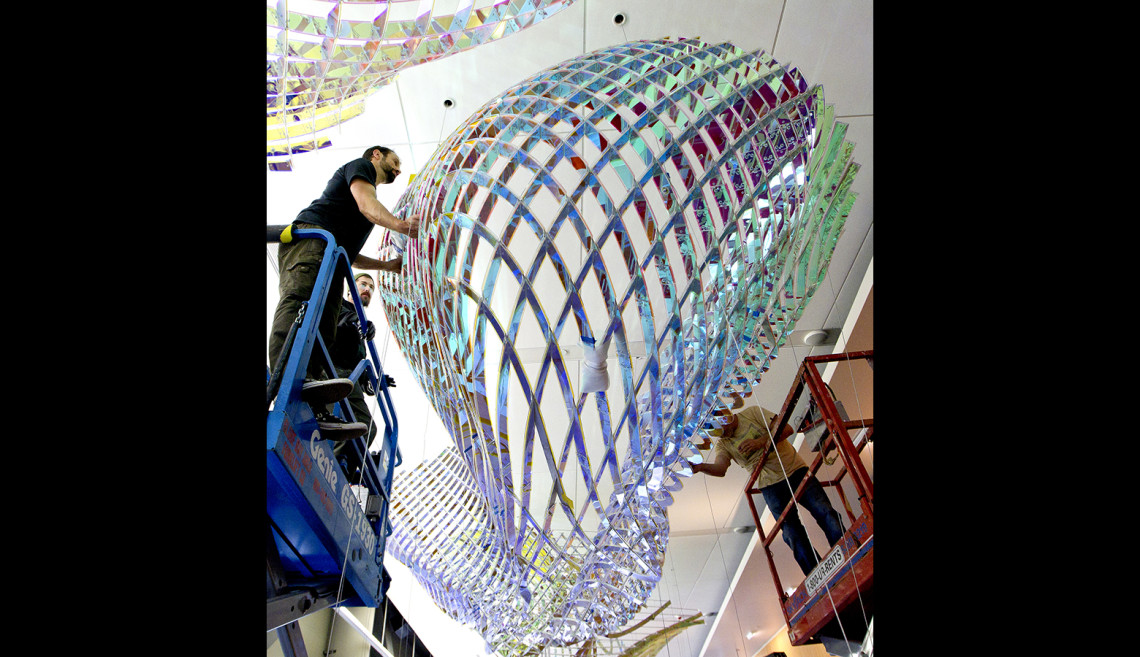 Workers install Three Fold, which hangs from the ceiling of the second floor of the Li Ka Shing Center for Learning and Knowledge. The sculpture, by artist Alyson Shotz, was dedicated May 21.