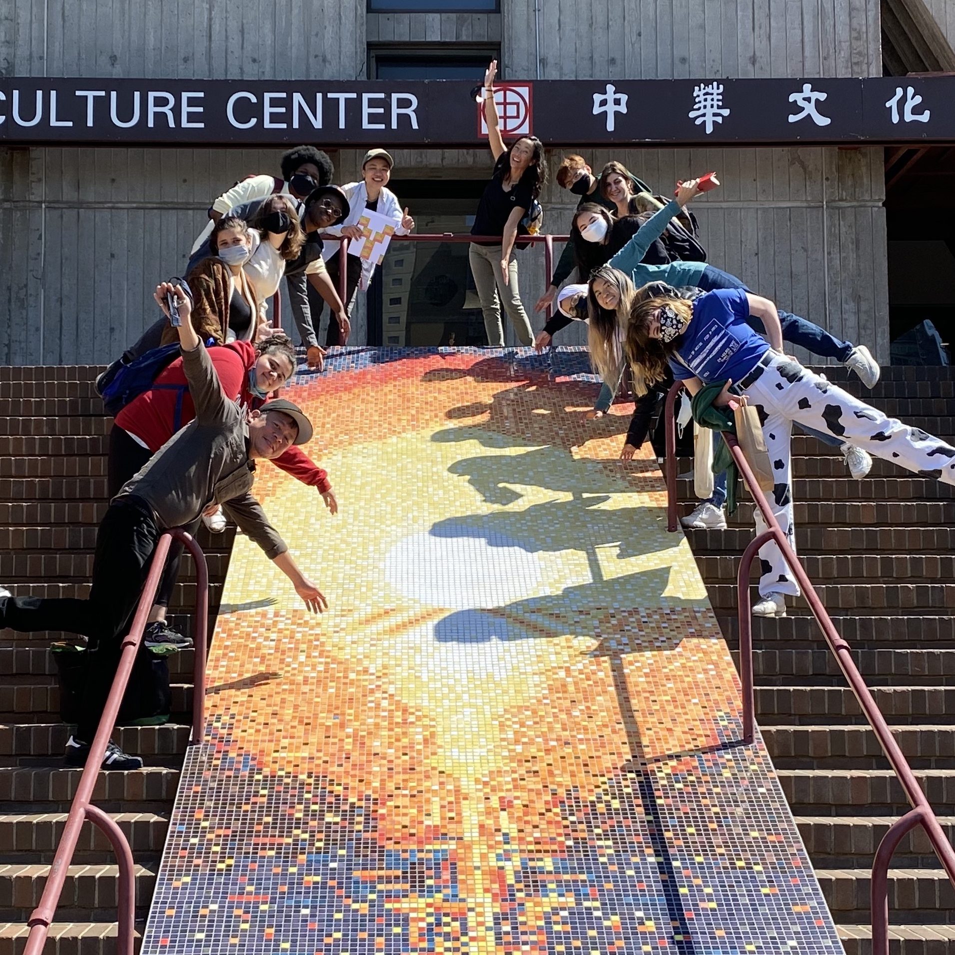 a group of students pose around a tile mosaic