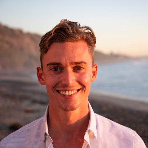 A person with short hair smiling at the camera