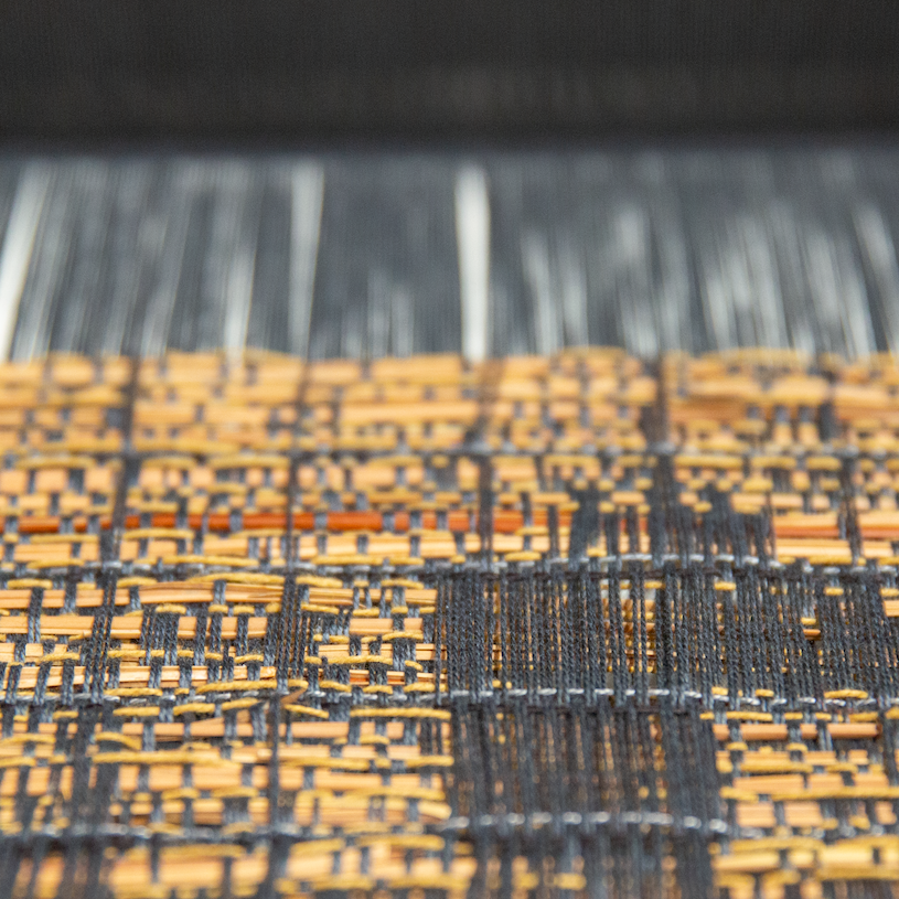 a close-up photo of a black and tan textile on the TC2 loom